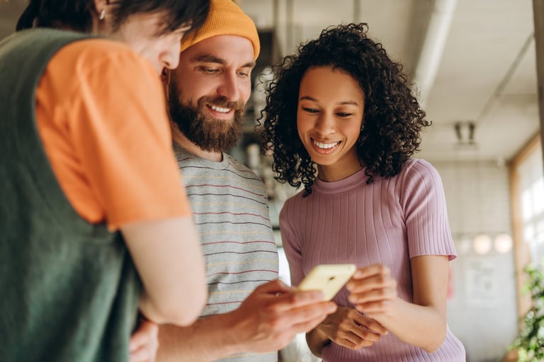Three young colleagues collaborating on a smartphone in a modern office